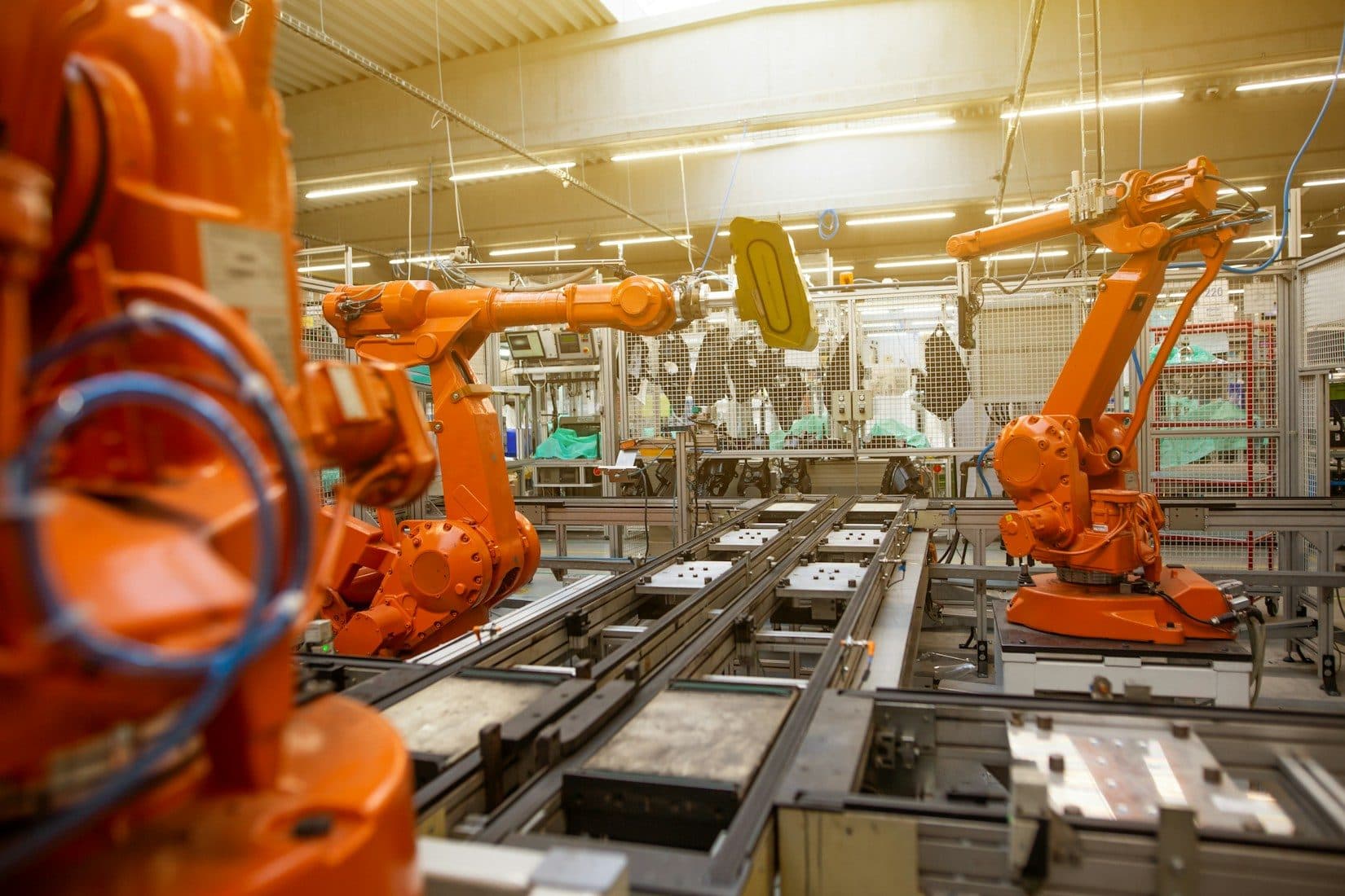 Orange industrirobotarme i arbejde langs en automatiseret produktionslinje