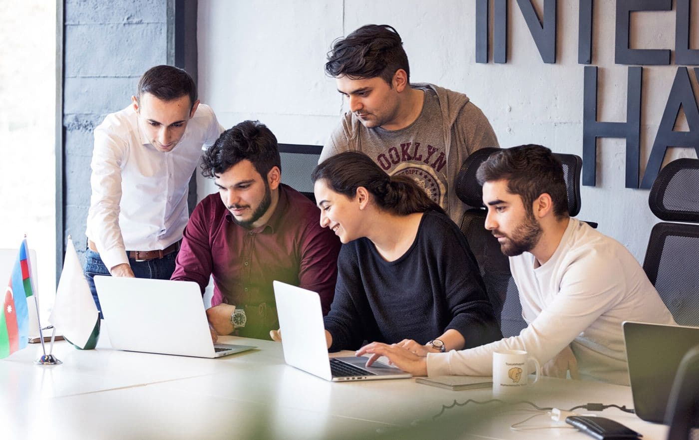 Das Team von Industrio Capital arbeitet im Büro gemeinsam an Laptops