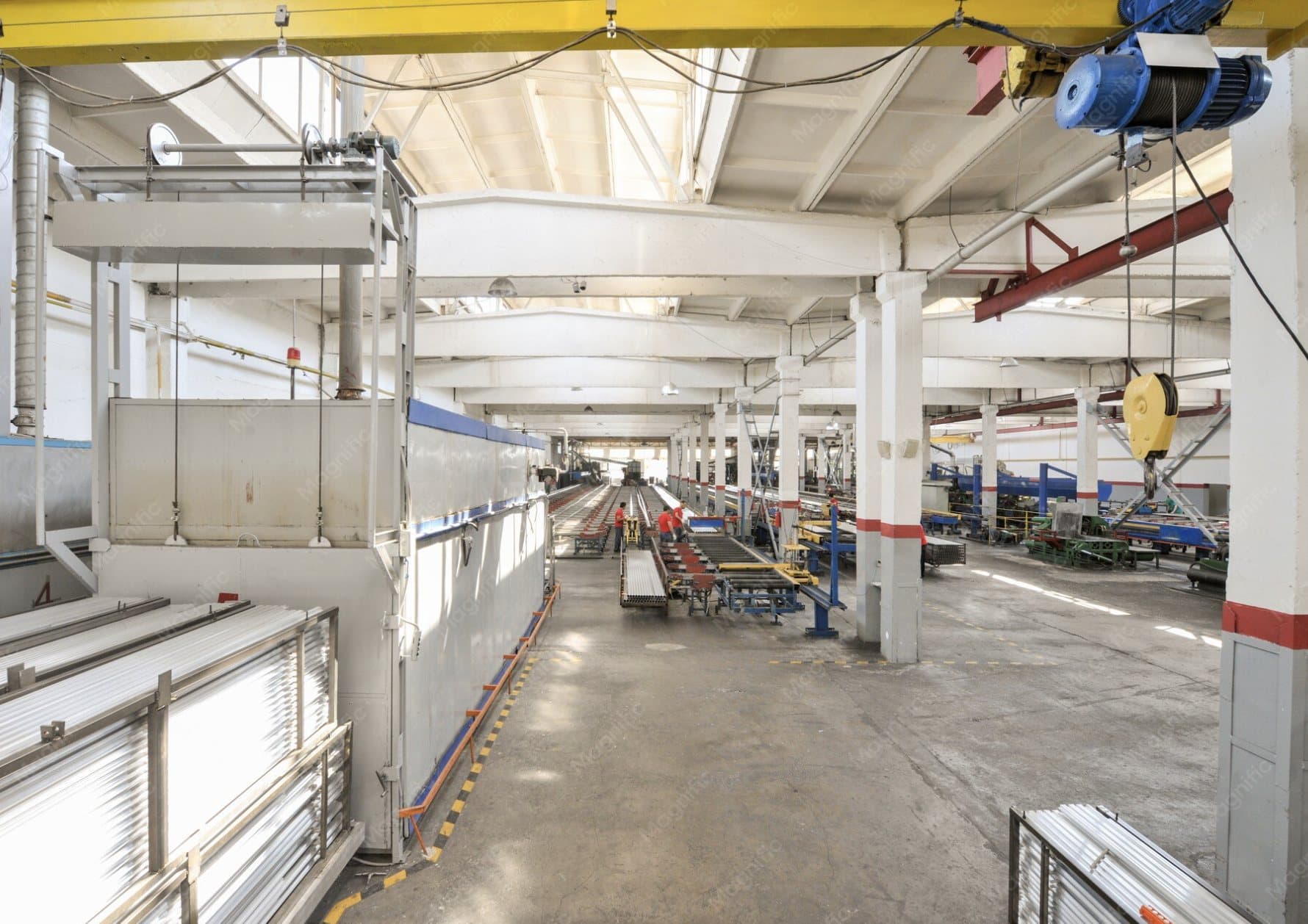 Industriel produktionshal med traverskraner og en central rullebane